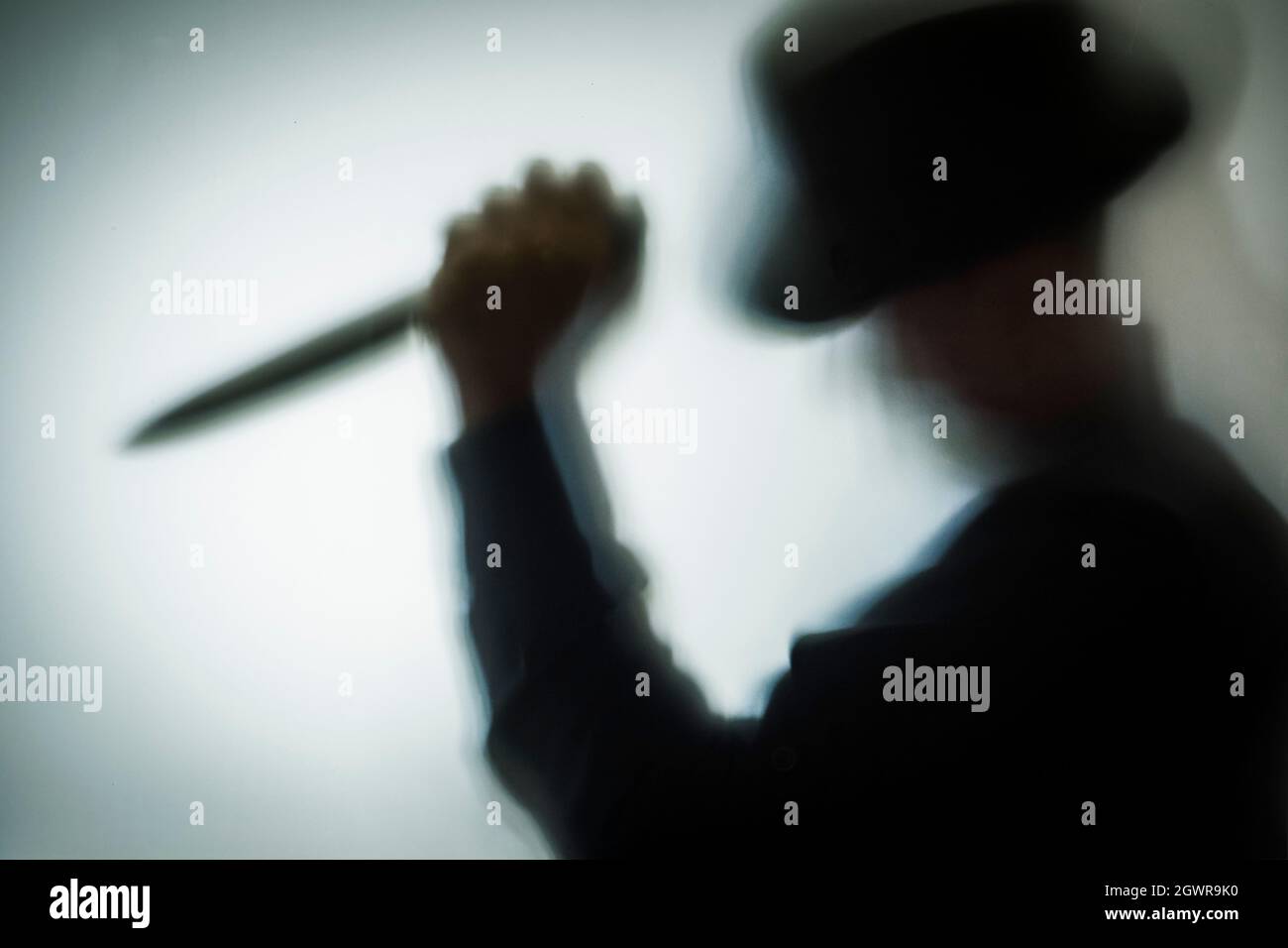 Man Killer With A Knife In His Hand And In A Hat, Silhouette Through The  Glass Stock Photo - Alamy
