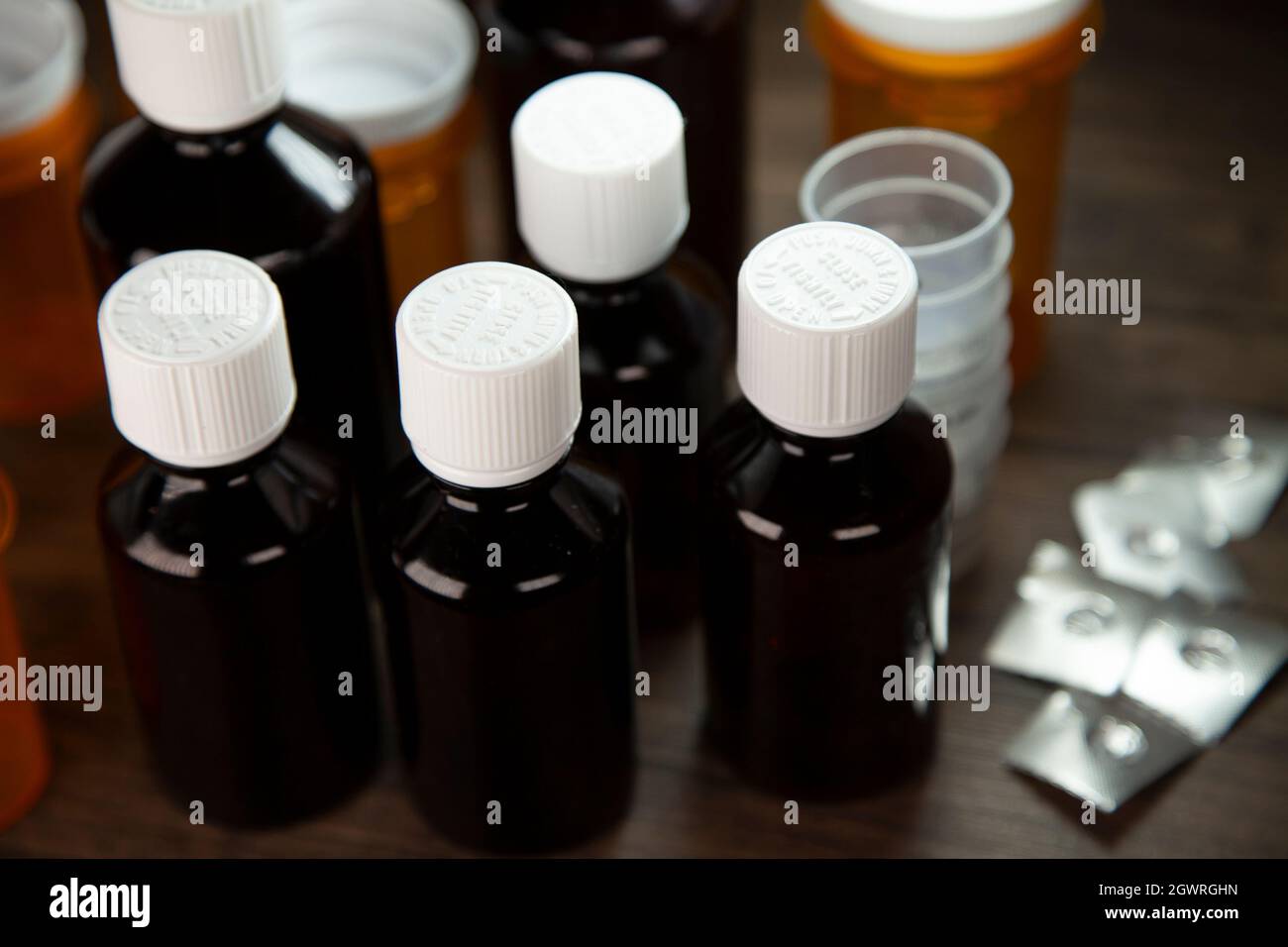 Cough syrup bottles, medicine cups, open medication blister packs, and