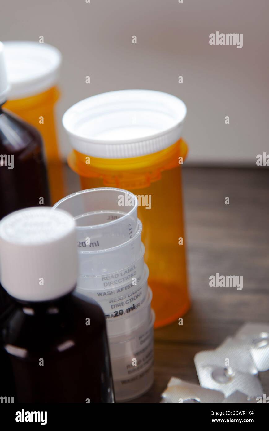 Cough syrup bottles, medicine cups, open medication blister packs, and