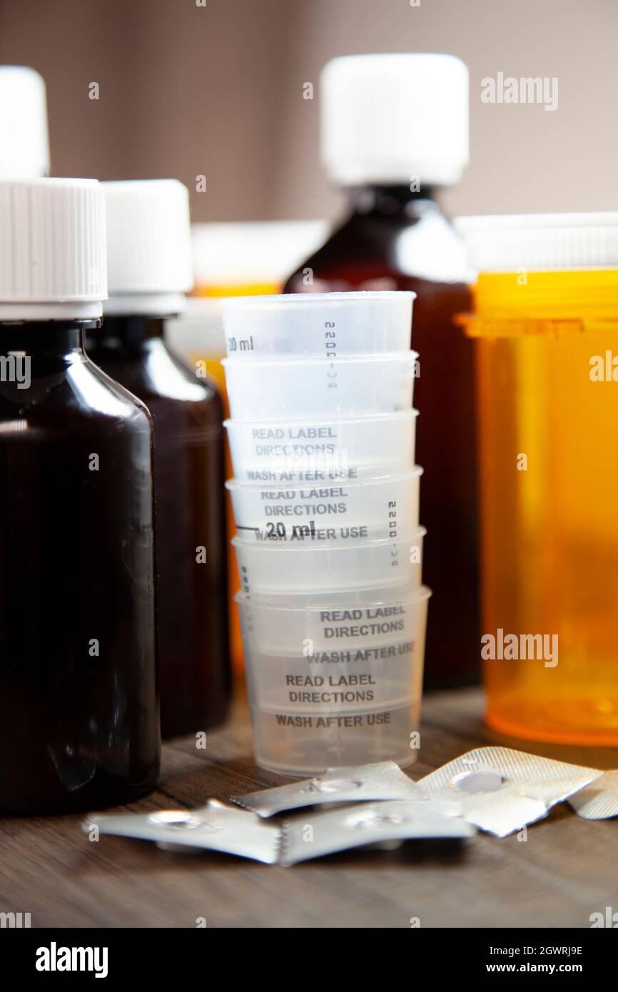 Cough medicine, medication cups, open and empty medication blister