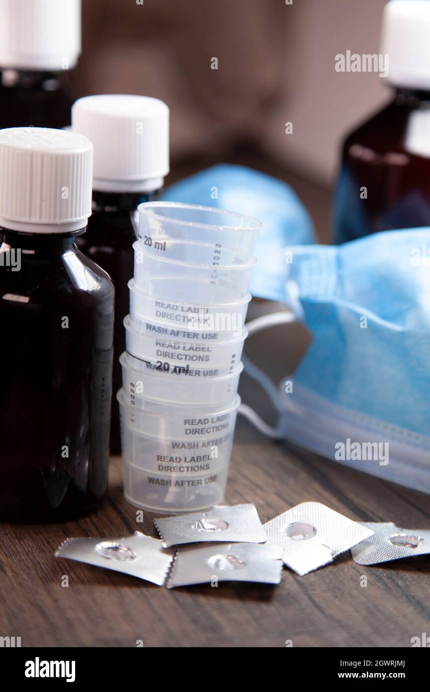 Cough medicine, medication cups, and open and empty medication blister