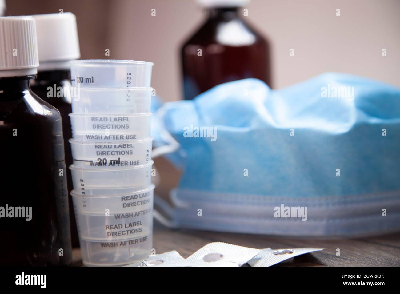 Cough medicine, medication cups, and open and empty medication blister