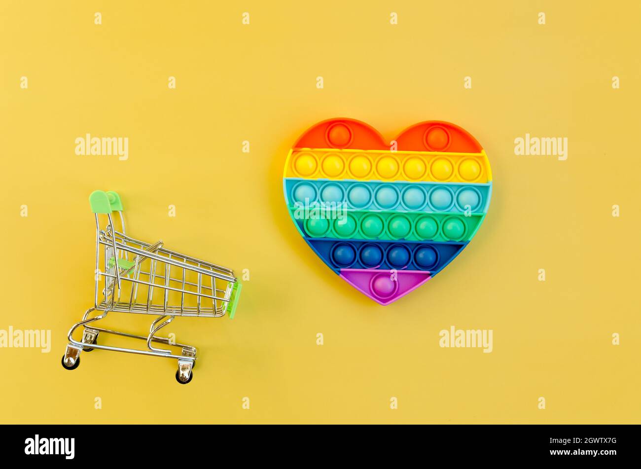 Top View Of Anti Stress Sensory Toy Pop It Rainbow Heart On Yellow Background. Popular, Trend Toys. Stock Photo