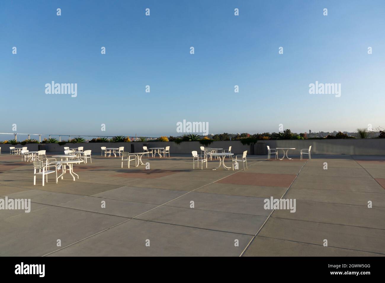 Set of white plastic outdoor chairs and tables on a rooftop. Seating