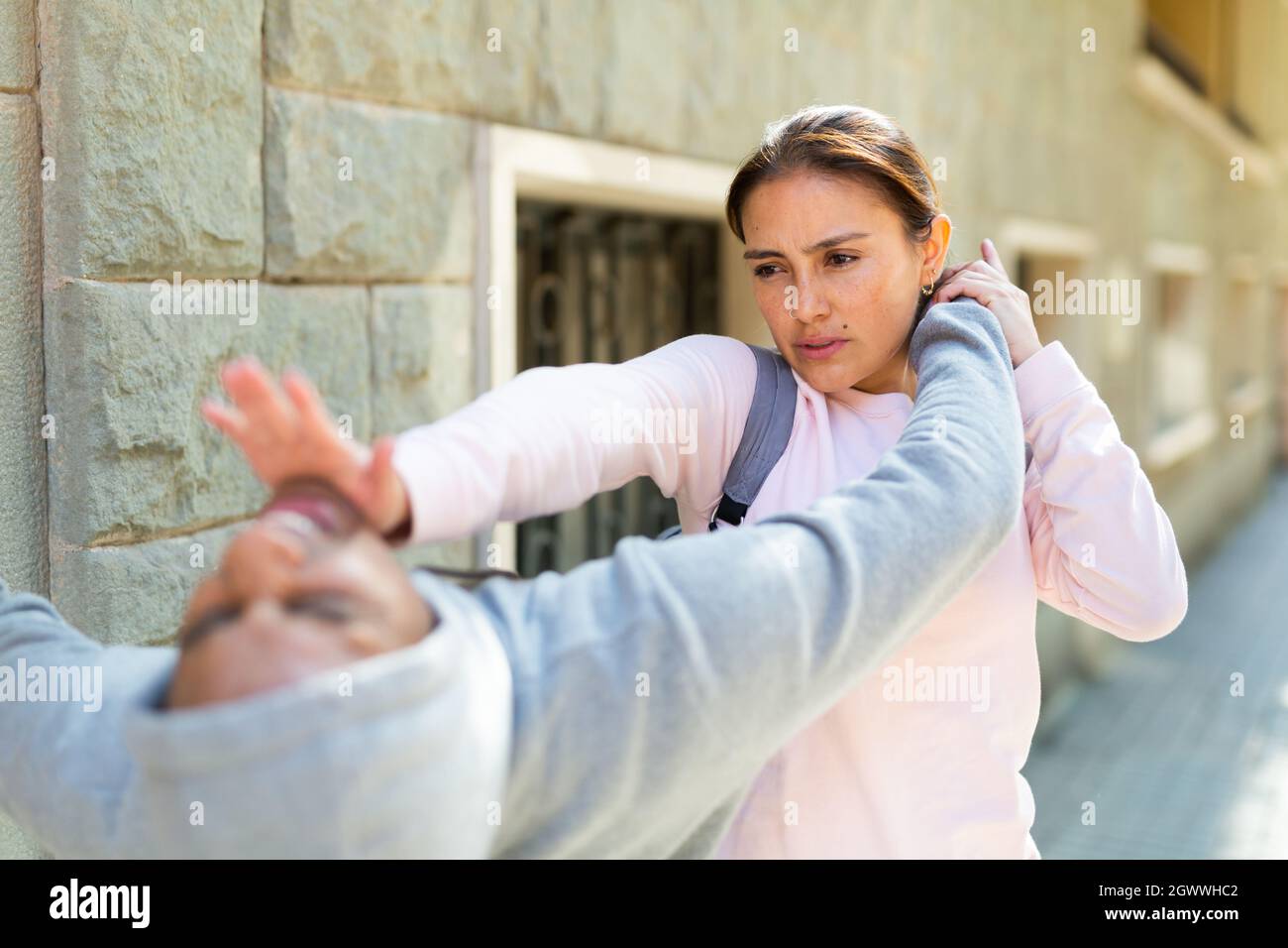 Strong woman using forceful blow in the eyes of rapist on street Stock Photo