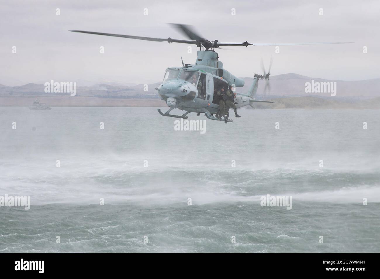 Members of the Fuerzas Armadas del Peru (Peruvian Armed Forces) helocast out of a UH-1Y Venom helicopter during an amphibious landing as part of UNITAS LXII in Salinas, Peru, Oct. 2, 2021. UNITAS is the world's longest-running maritime exercise. Hosted this year by Peru, it brings together multinational forces from twenty countries and includes 29 ships, four submarines, and twenty aircraft conducting operations off the coast of Lima and in the jungles of Iquitos. The exercise trains forces to conduct joint maritime operations and focuses on strengthening partnerships and increasing interopera Stock Photo