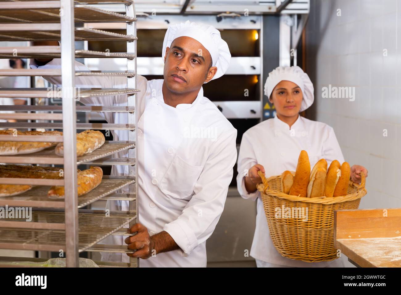 Man baker transporting a cart with bread in bakery Stock Photo - Alamy