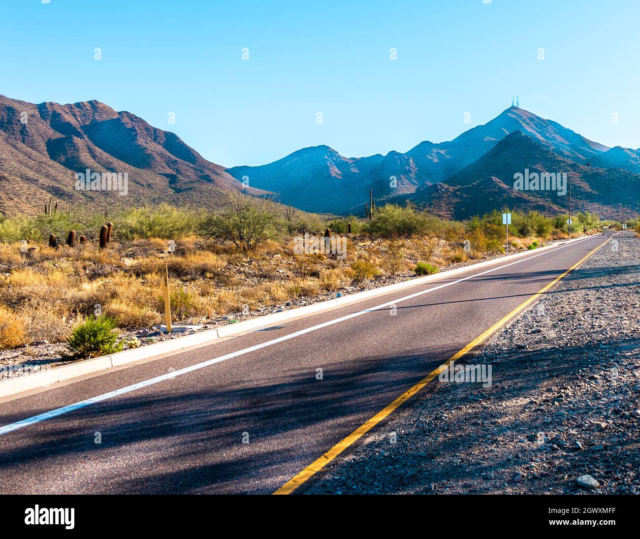 Road Leading Towards Mountains Against Clear Sky Stock Photo