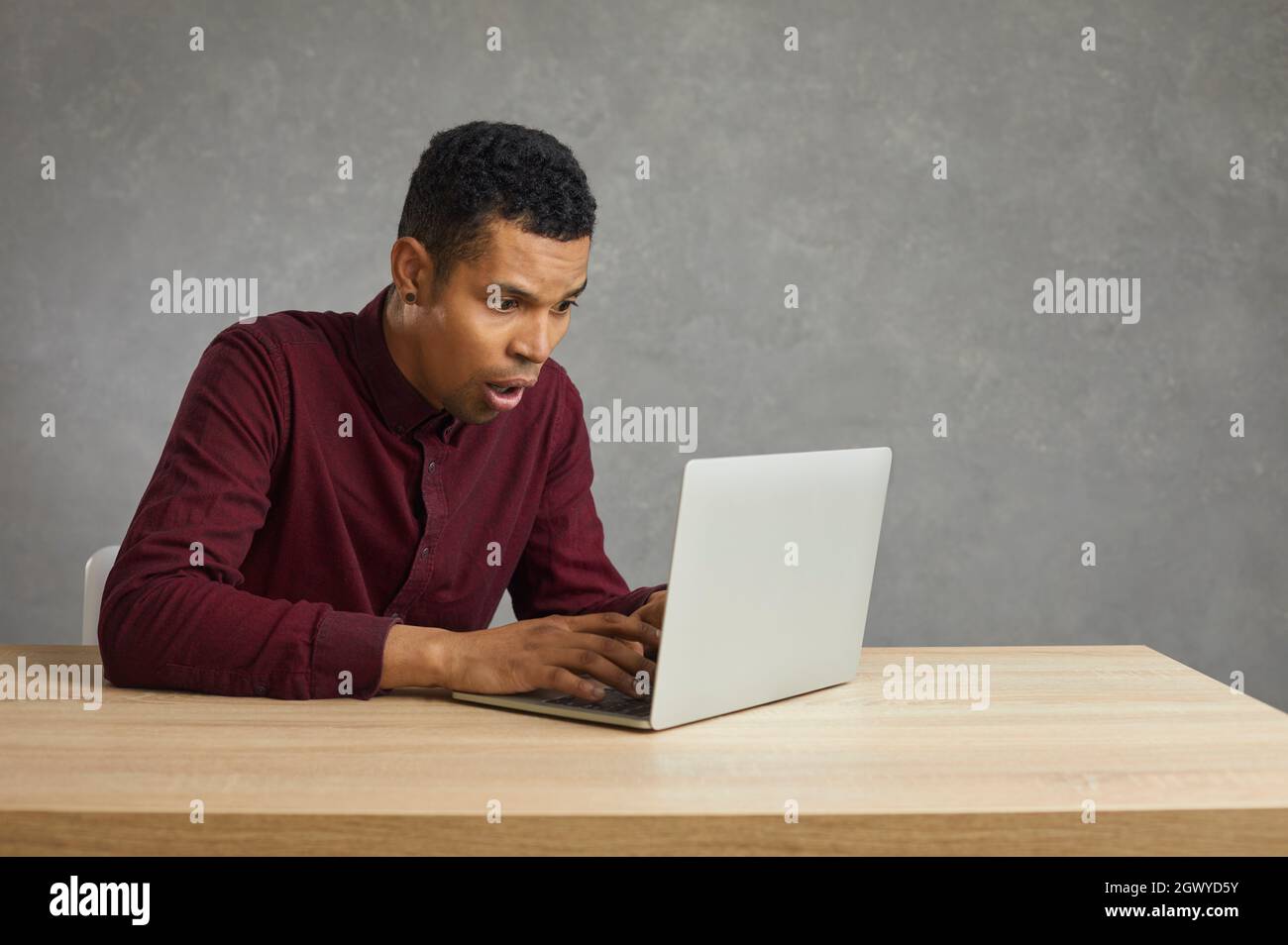 Young African American man in trouble due to computer error or software problem on laptop Stock Photo