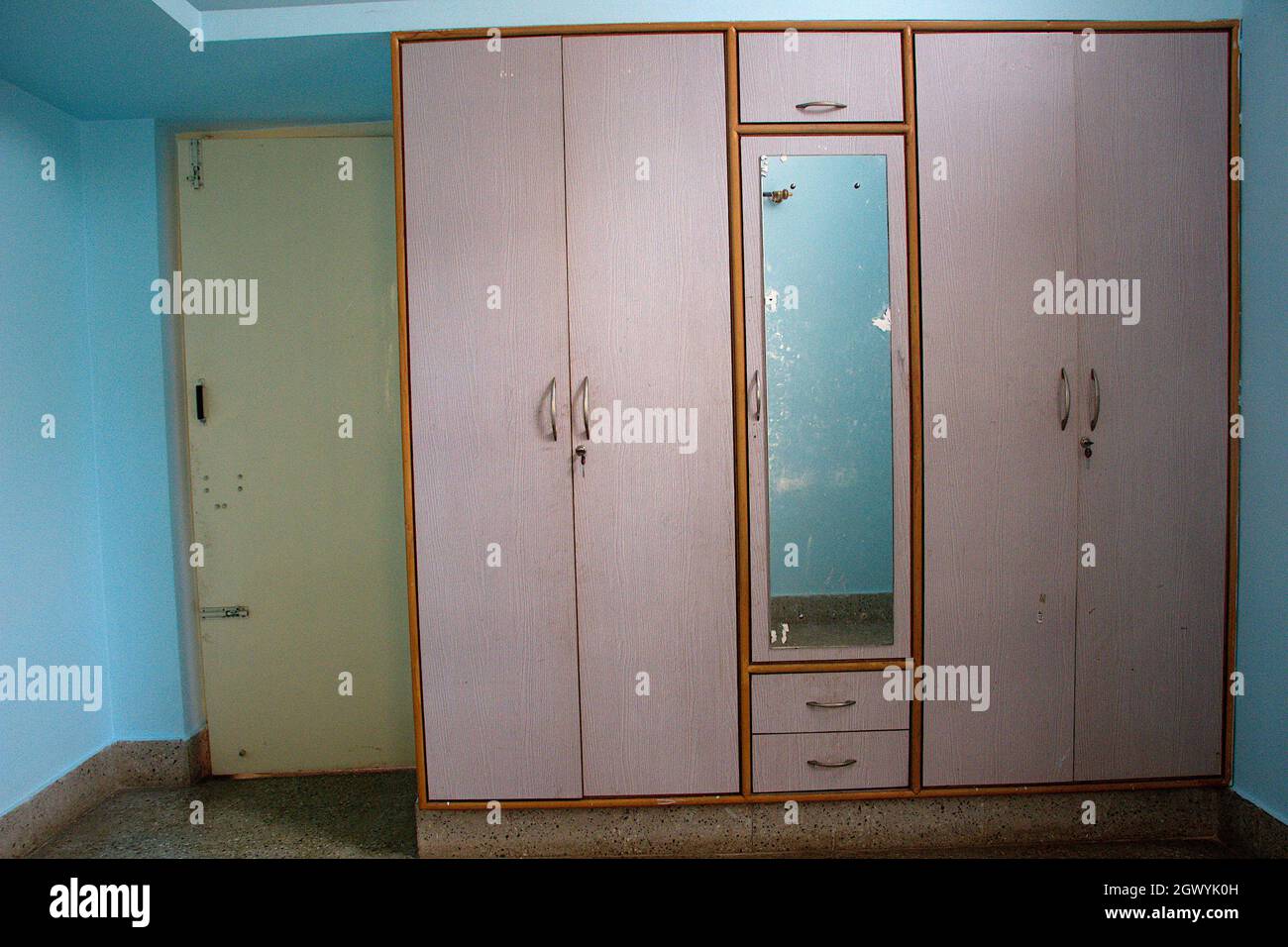 Interior of room showing closed door and wardrobe with dressing mirror Stock Photo