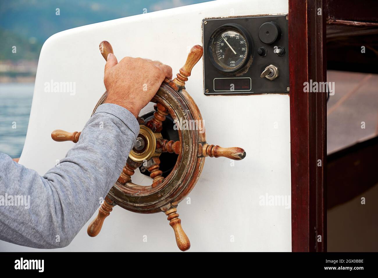 The captain's hand steers the ship helm. Voyages and adventures at sea