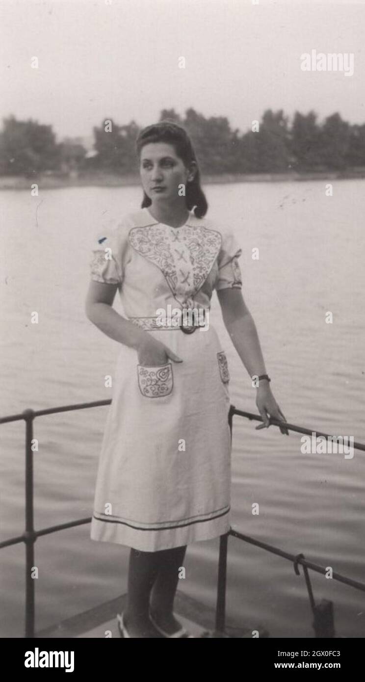 vintage photo: Young pretty lad is standing on a boat which is going cross the river. The lady is wearing a nice hungarian folklore close but not the traditional one rather than the fashionable one which was popular at the 1930's. Source: original photograph Stock Photo