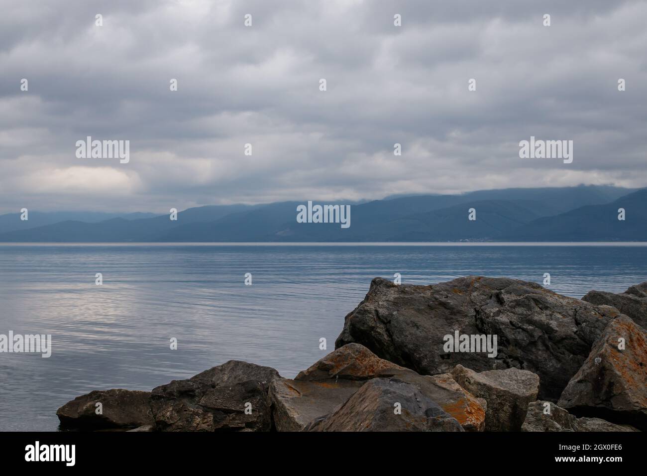 Lake Baikal In Cloudy Weather, Irkutsk Region, Russia. In The Foreground Are Large Stones. Stock Photo