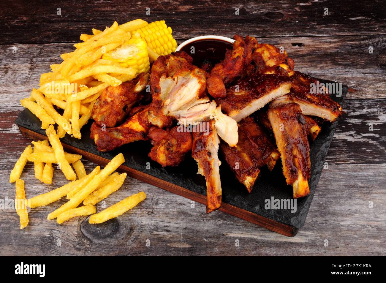 Barbecue pork ribs and chicken wings with French fries and sweetcorn on