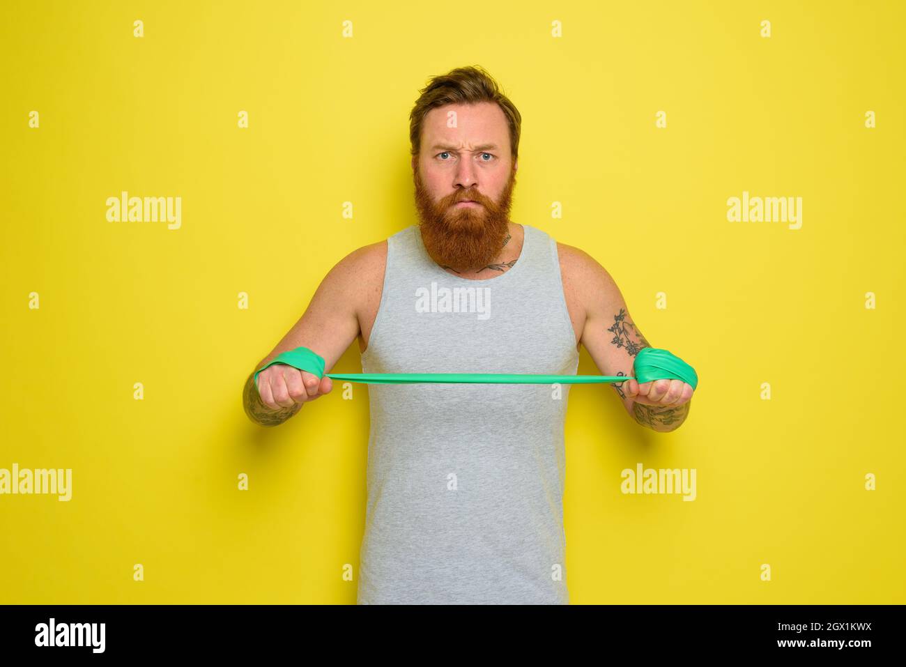 Man with beard and tattoos trains with a rubber band Stock Photo Alamy