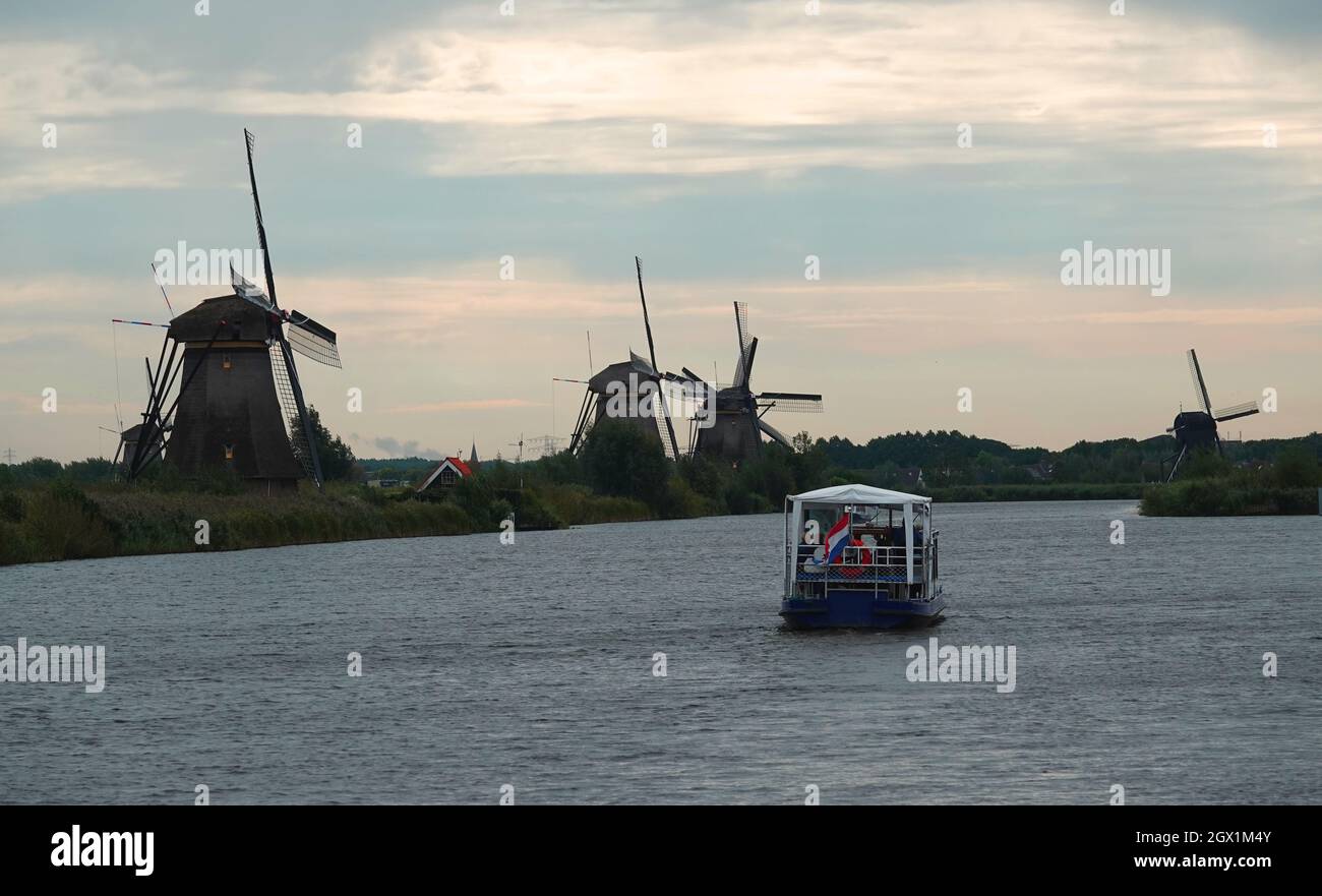 Tour boat on a canal with the famous Dutch windmills at Kinderdijk: an UNESCO world heritage site. Stock Photo