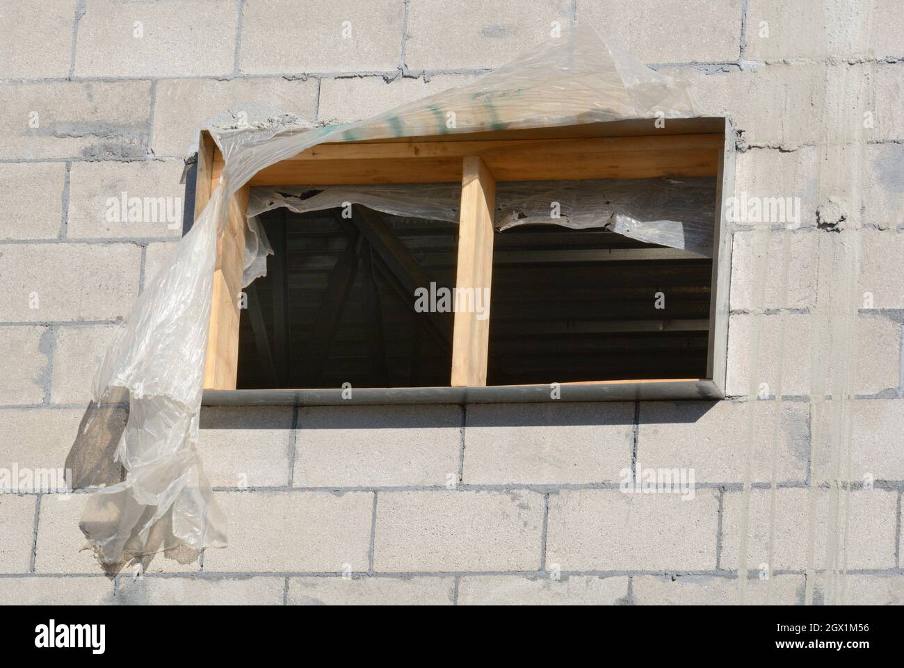 Window frame with plastic still attached in cinder block building