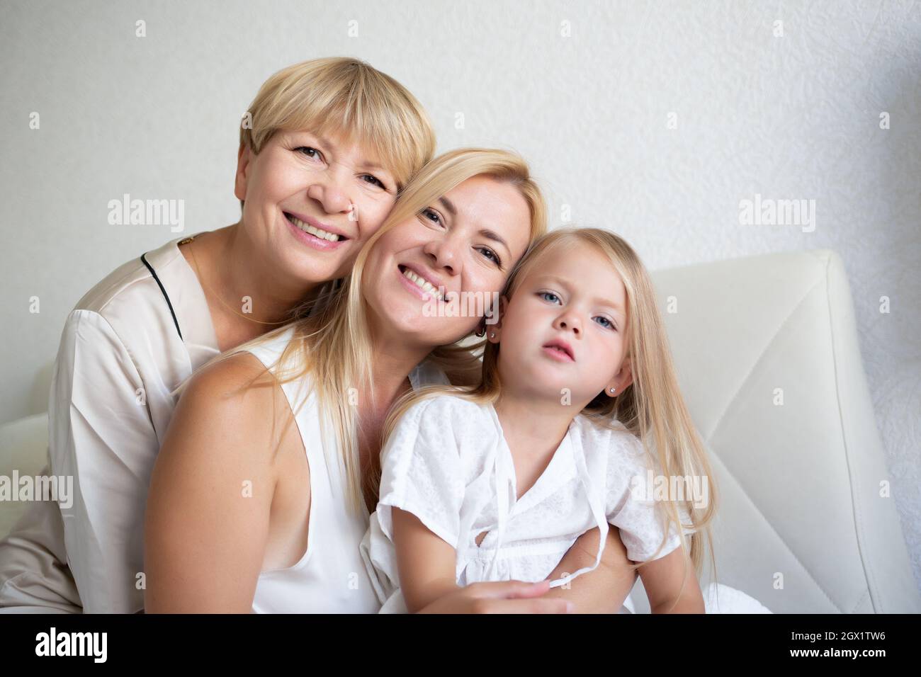 family portrait: mom, daughter and granddaughter are sitting on the bed