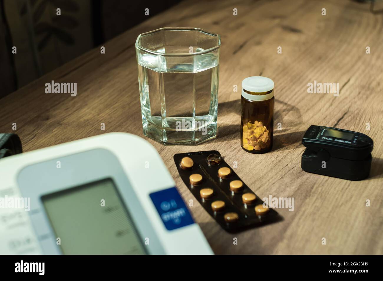 Close-up of a glass of water, pills, a blood pressure monitor and an oxyometer. Selective focus. The concept of health Stock Photo