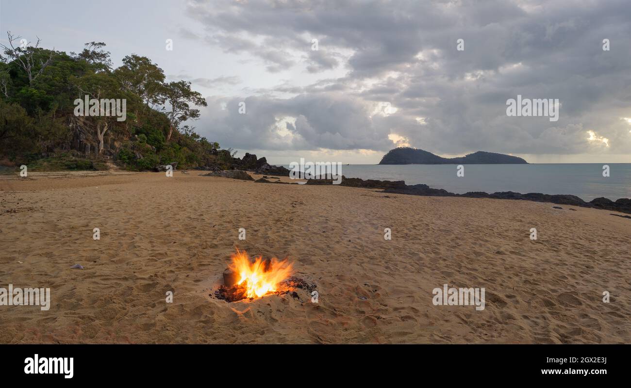 Evening panoramic landscape of Palm Cove's northern rocky point and double Island with a beach campfire in progress north of Cairns in QLD, Australia. Stock Photo