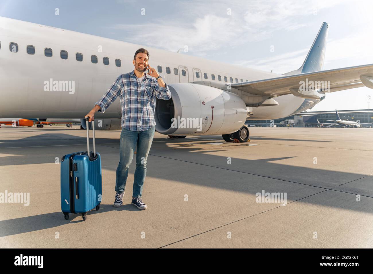 Smiling man using smartphone near airplane outdoor Stock Photo