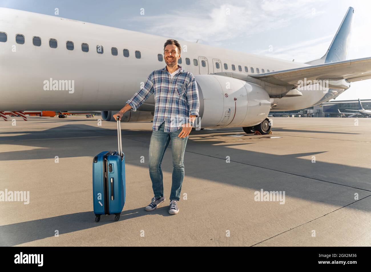 Happy adult man at the airport with suitcase Stock Photo