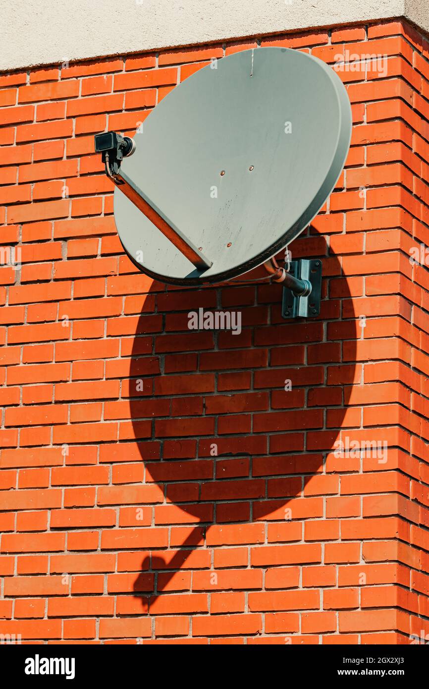 Old satellite dish mounted on house brick wall, selective focus Stock Photo