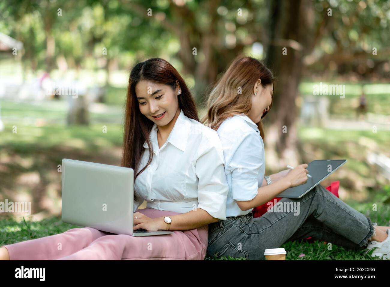Woman students studying in a group project in the park of university or school. Happy learning, community teamwork and youth friendship concept Stock Photo