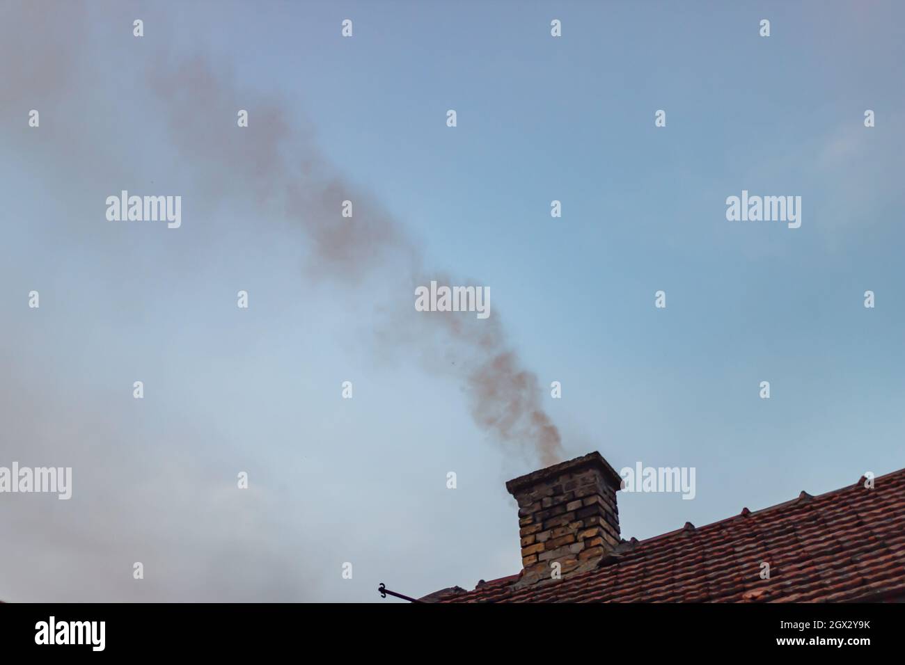 Smoke coming out of the chimney on the roof Stock Photo
