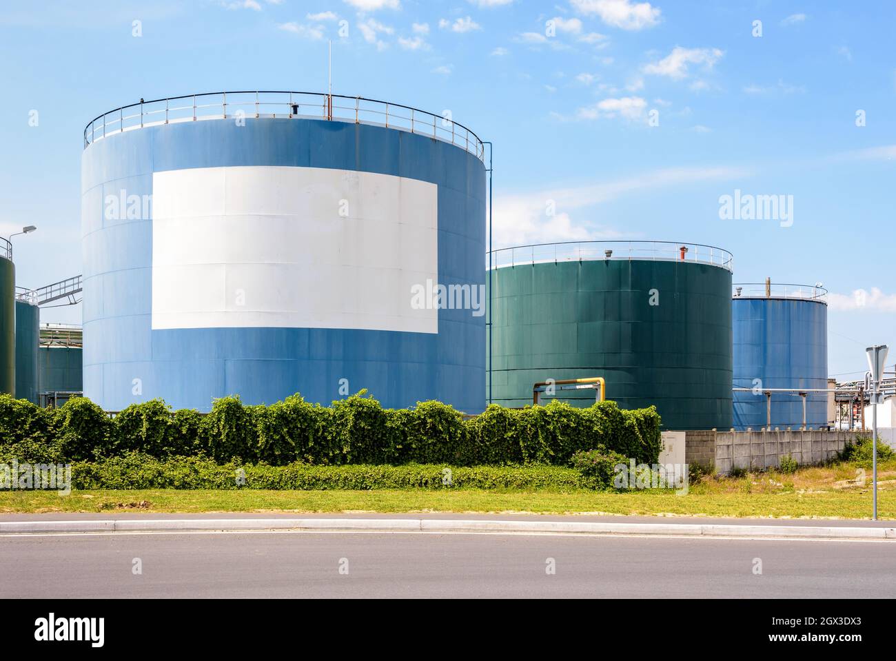 Large coloured storage tanks for oil and fuel in a tank farm with a white blank copy space under a blue sky. Stock Photo
