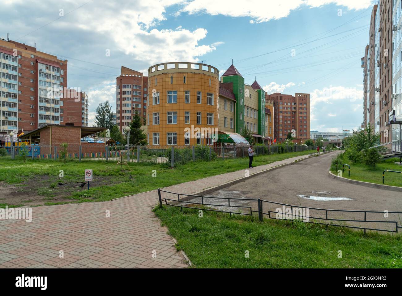 The kindergarten building stands in the neighborhood between residential buildings on a summer day. Stock Photo