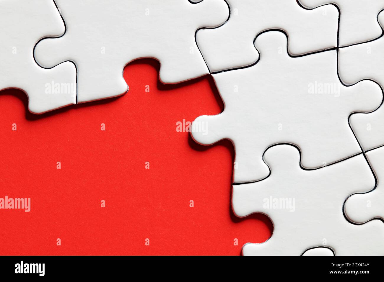 Empty red background surrounded by white jigsaw puzzle pieces with copy space. Stock Photo