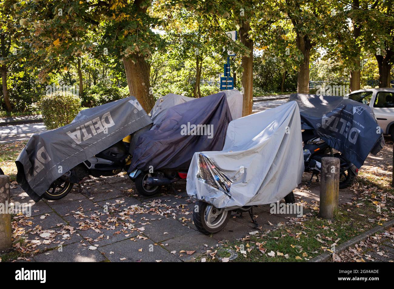 parked motorbikes and scooters under tarpaulins at the roadside in Hagen-Vorhalle, Hagen, North Rhine-Westphalia, Germany.  geparkte Motorrraeder und Stock Photo