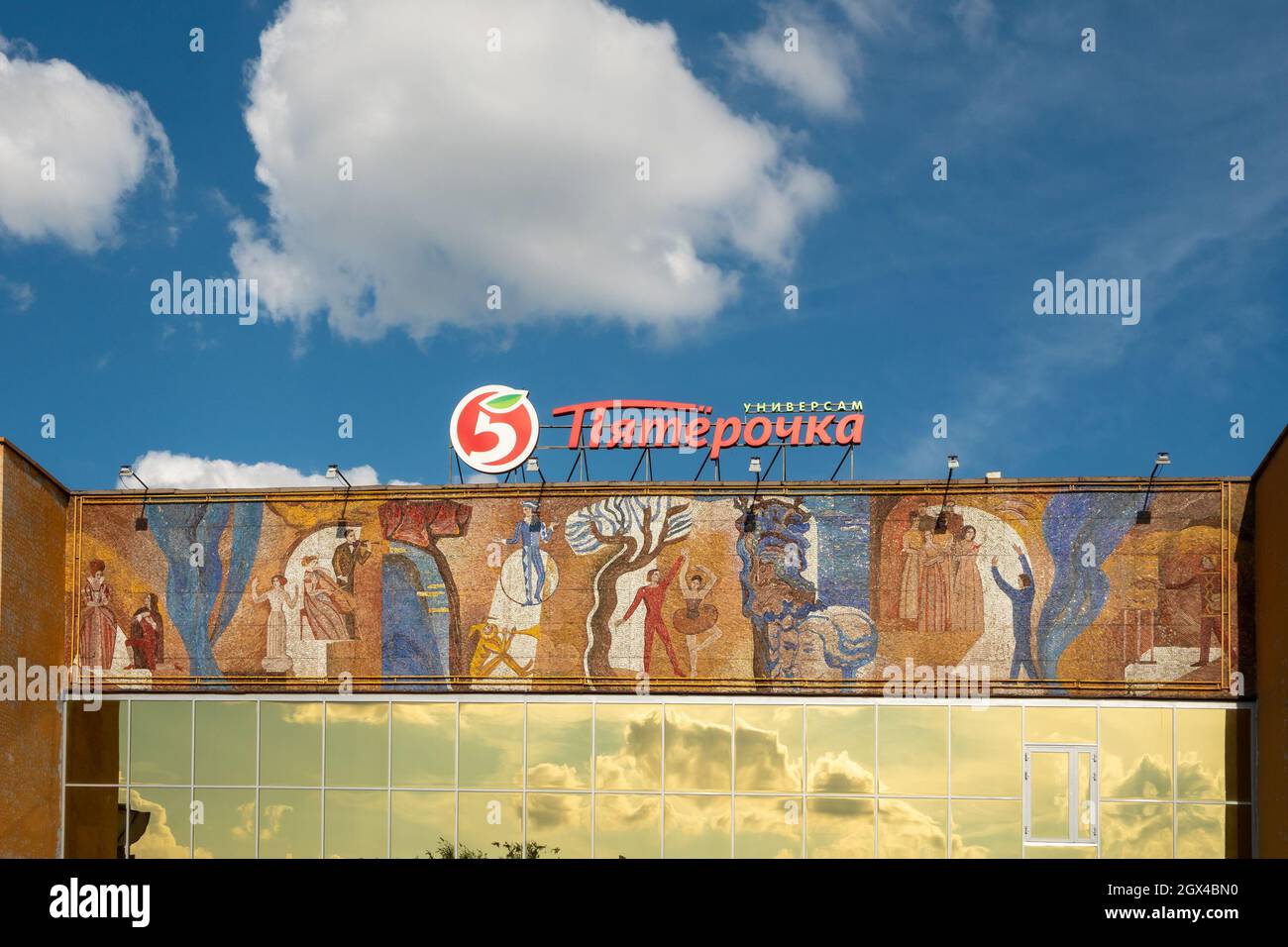 The wall of the former House of Culture of Combine Builders with a mosaic of Soviet times and with the logo and the name of the Pyaterochka supermarke Stock Photo