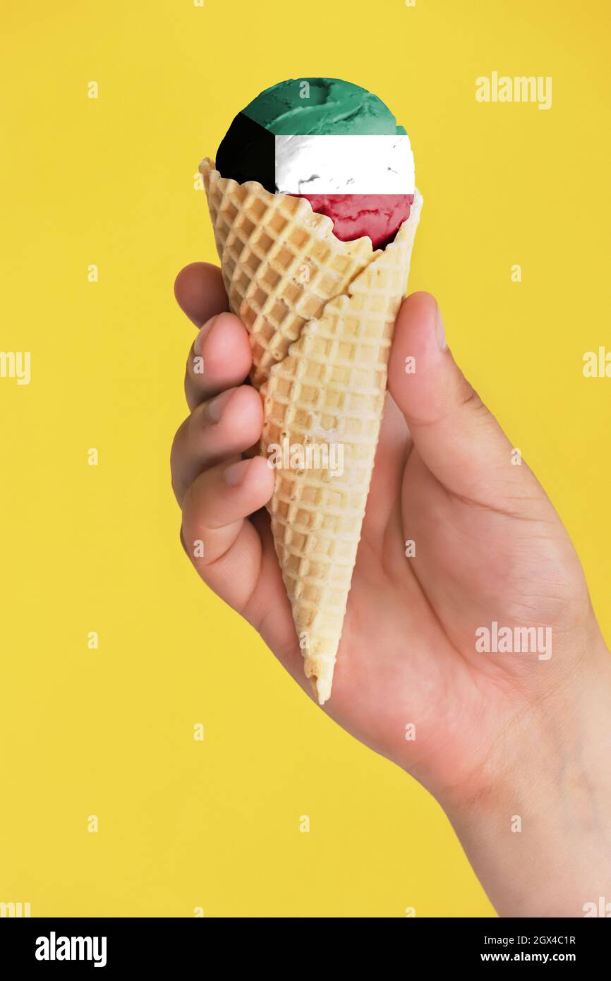 On a colorful background, a hand with ice cream in the form of the flag