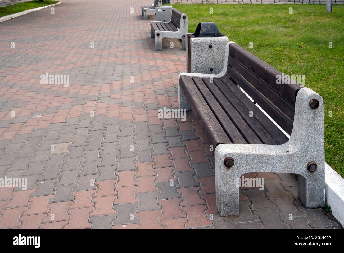 Street wooden benches with a marble base have been standing since Soviet times on a cobbled sidewalk in a city street Stock Photo