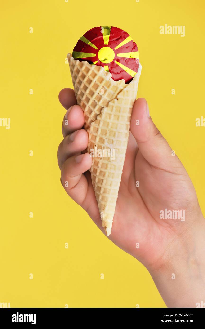 On a colorful background, a hand with ice cream in the form of the flag