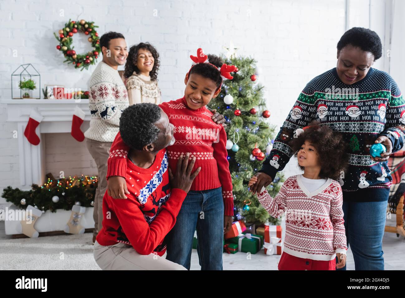 happy african american grandparents talking to kids in living room with christmas tree Stock Photo