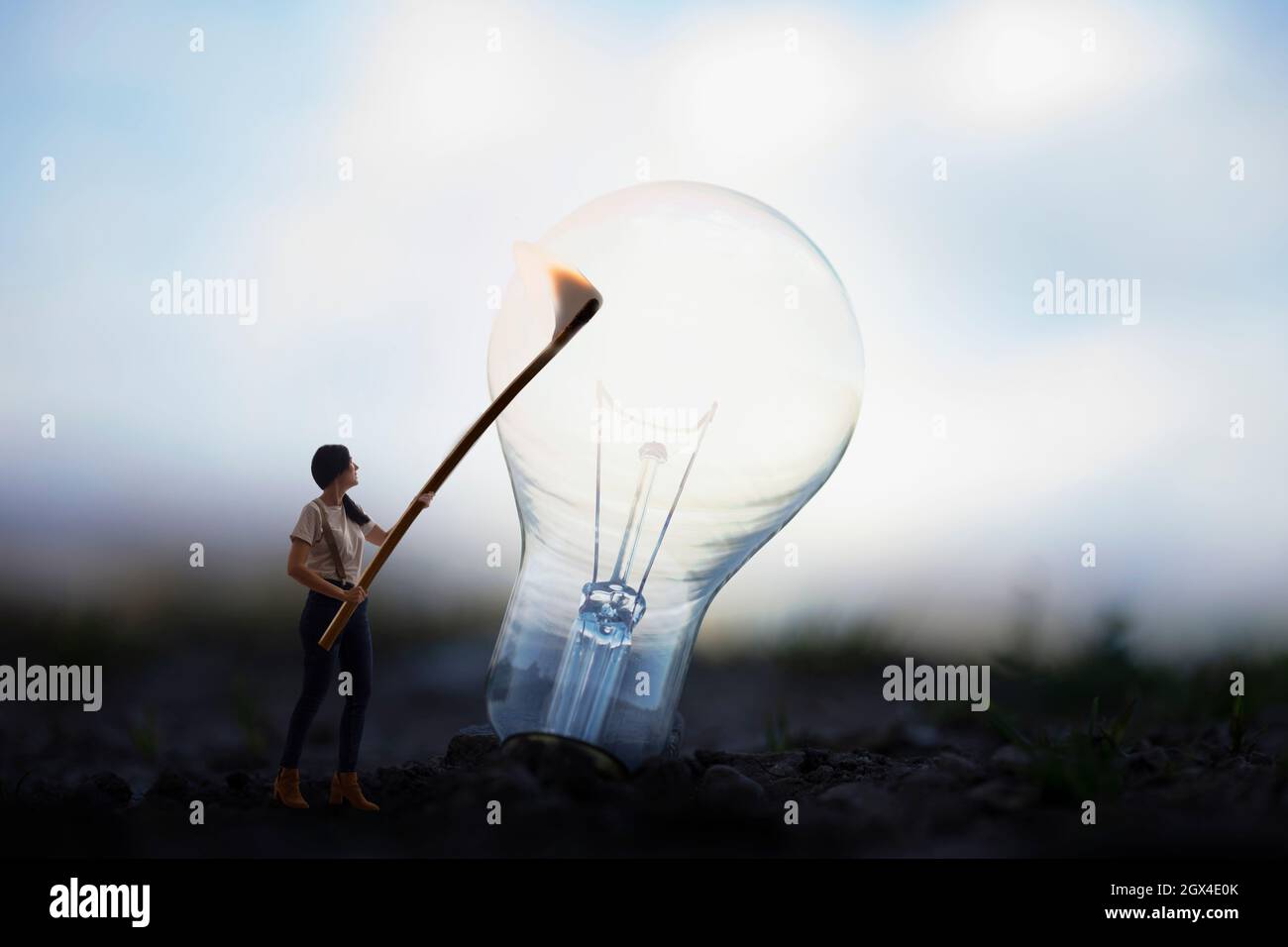 woman tries to light a light bulb with a match, concept of idea and innovation Stock Photo