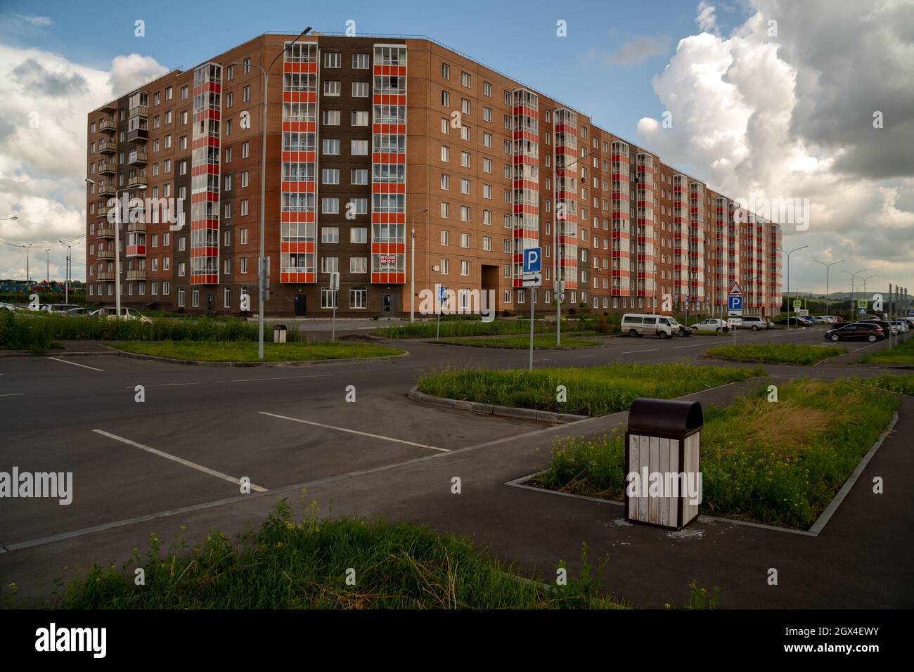 Residential apartment building and parked cars in a parking lot nearby in the new Yasny microdistrict. Stock Photo