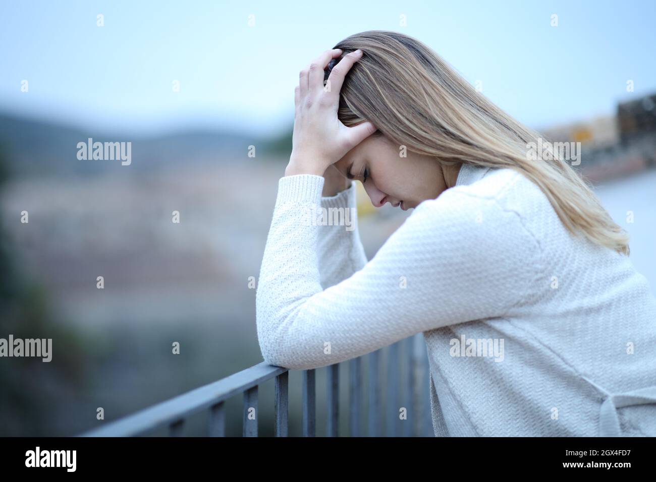 Side view portrait of a depressed woman complaining in balcony Stock Photo