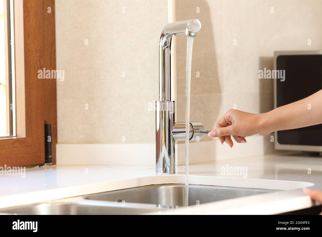 Close up of a woman hand opening kitchen faucet Stock Photo