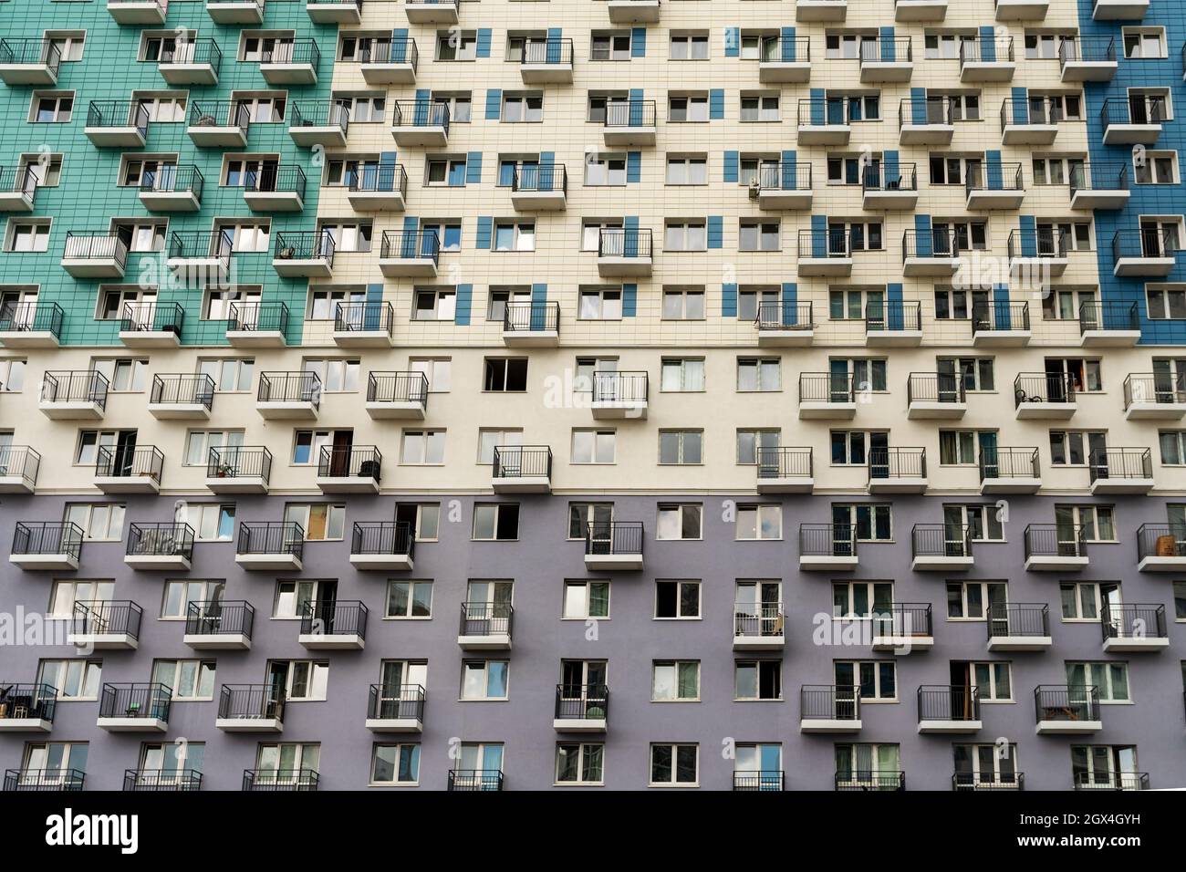 The facade of a multi-apartment new residential building with balconies and windows, painted in 3 colors. Stock Photo