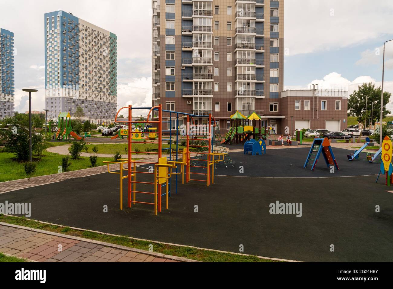 Children's playground and sports ground in the courtyard of a new residential building against the background of other houses on a summer day. Stock Photo