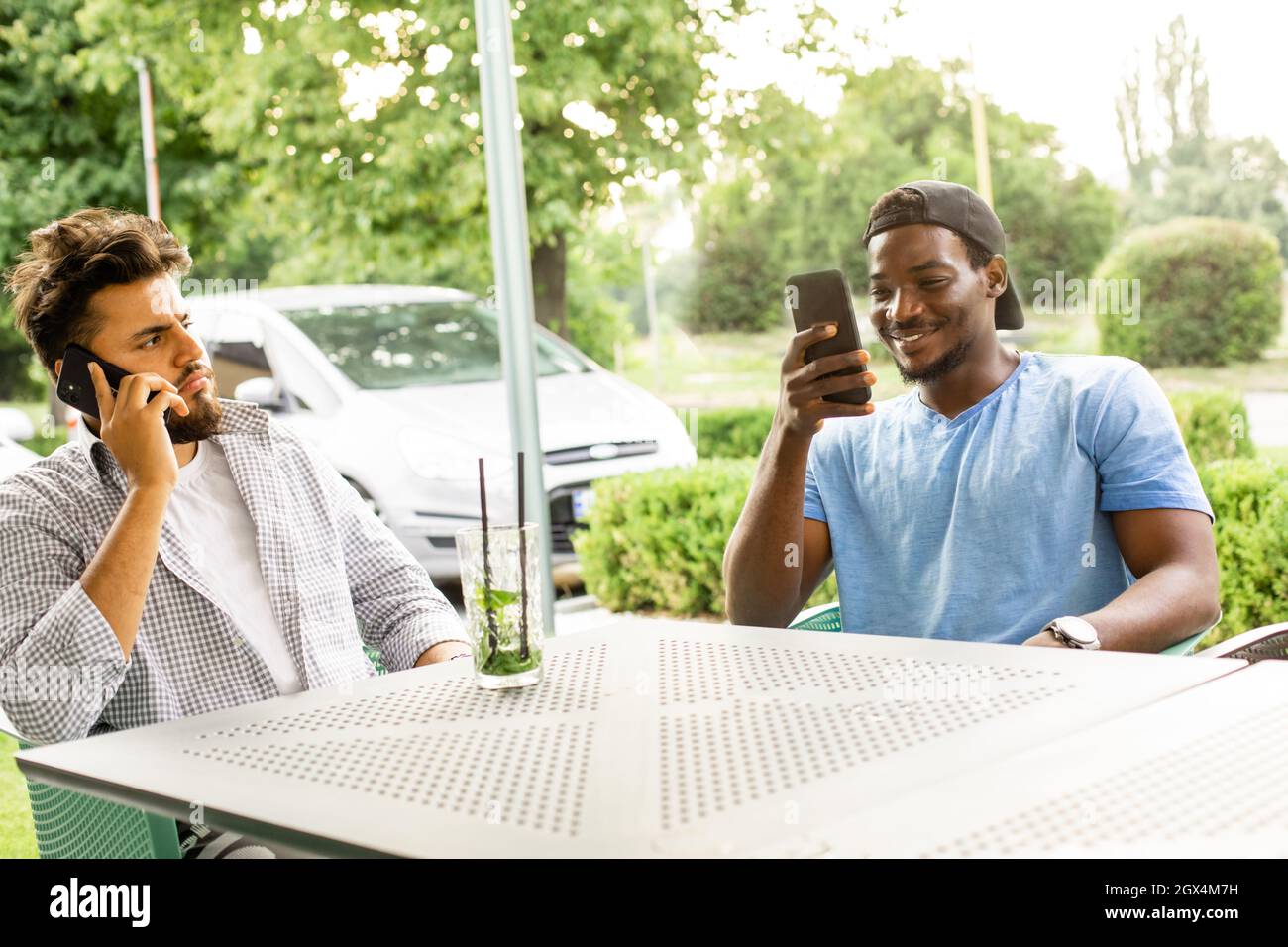 Diverse young friends talking via video call outdoors Stock Photo