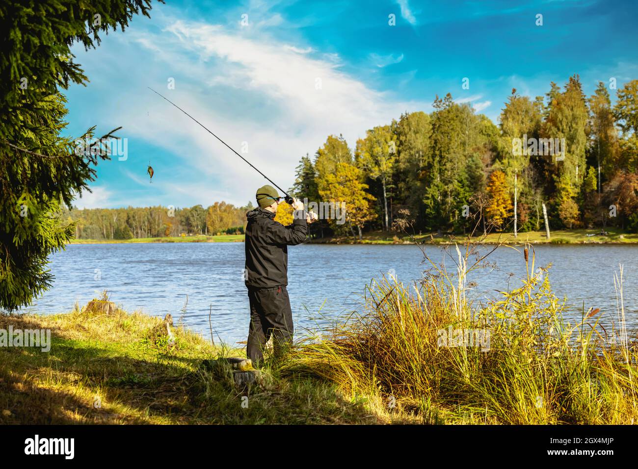 fisherman cast a spinning rod into the lake on sunny day. bank fishing Stock Photo