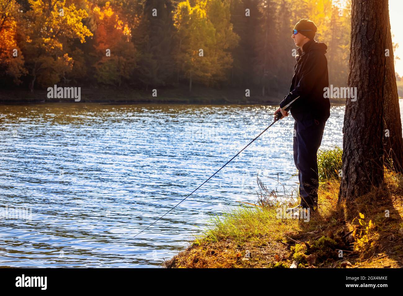 fisherman fishing in the lake from shore on sunny autumn day Stock Photo