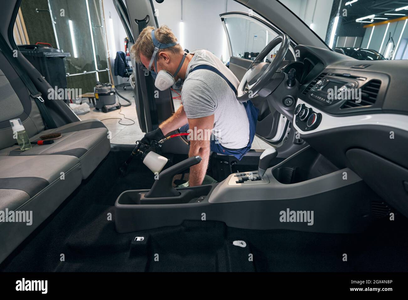 Car interior chemical cleaning by professional detailer in respirator ...