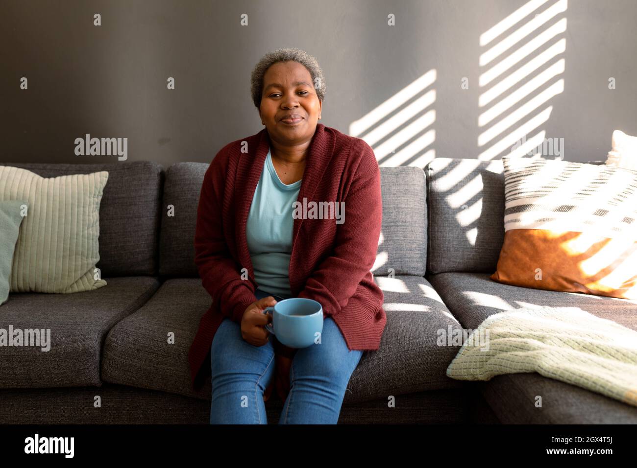 Relaxed african american senior woman sitting on sofa and drinking ...