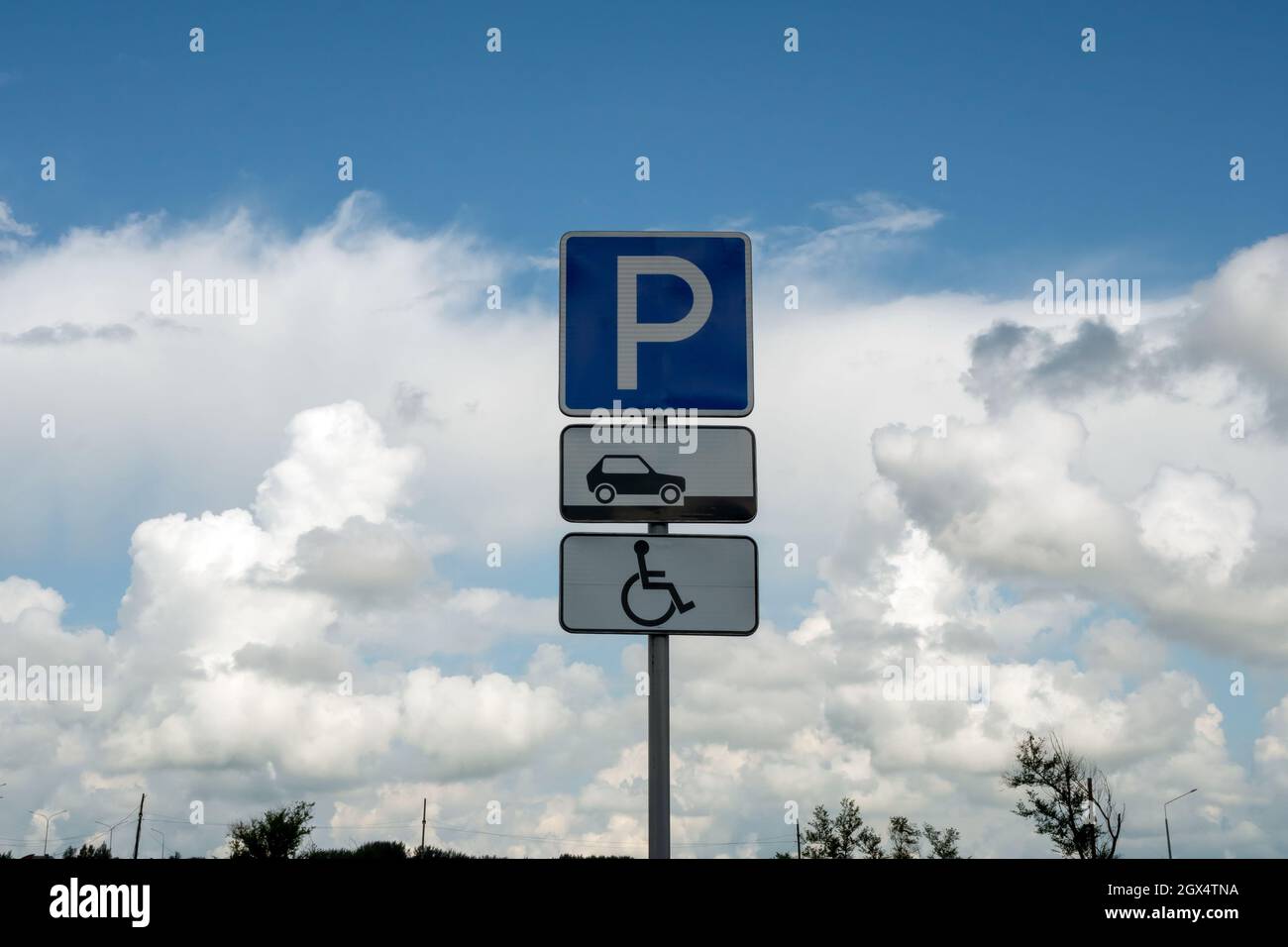 Road sign Disabled parking on the background of a beautiful cloudy summer sky. Stock Photo